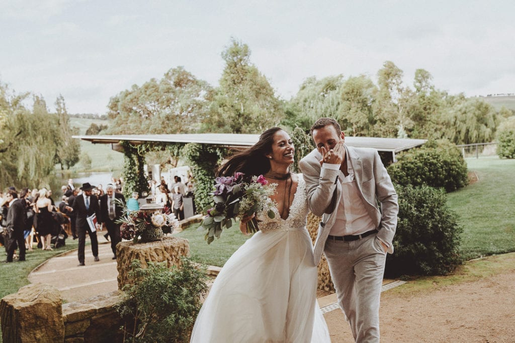 groom kissing hand of bride as they run from the ceremony